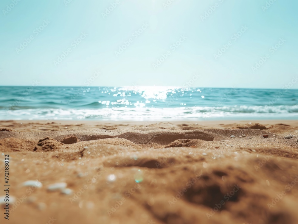 A beach with a clear blue sky and the ocean. The sand is dry and the water is calm A beach with a clear blue sky and the ocean. The sand is dry and the water is calm