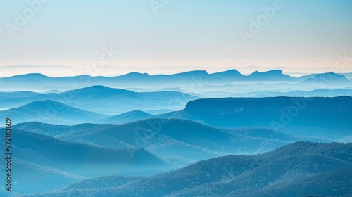 Layers of mountain ridges fade into the distance, their contours highlighted by a gentle haze, evoking a sense of serene vastness.