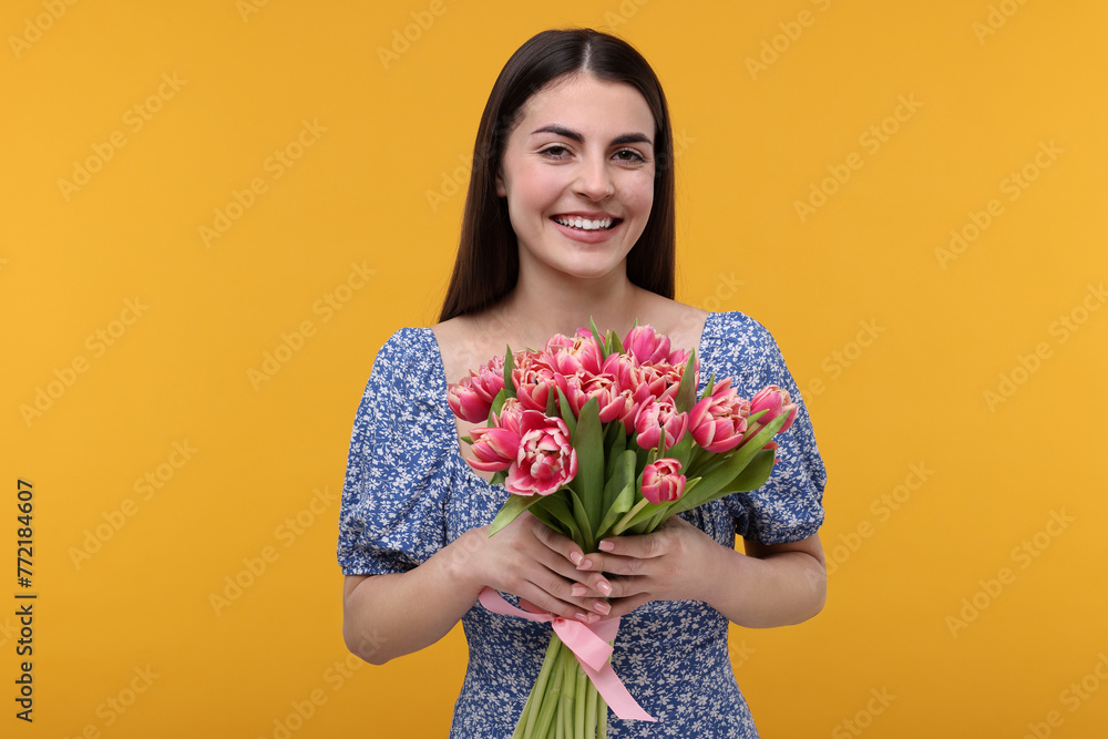 Happy young woman with beautiful bouquet on orange background Happy young woman with beautiful bouquet on orange background