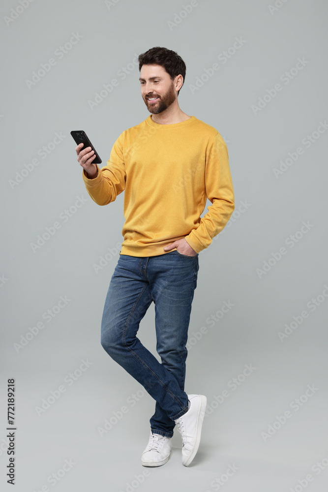 Smiling man with smartphone on grey background Smiling man with smartphone on grey background