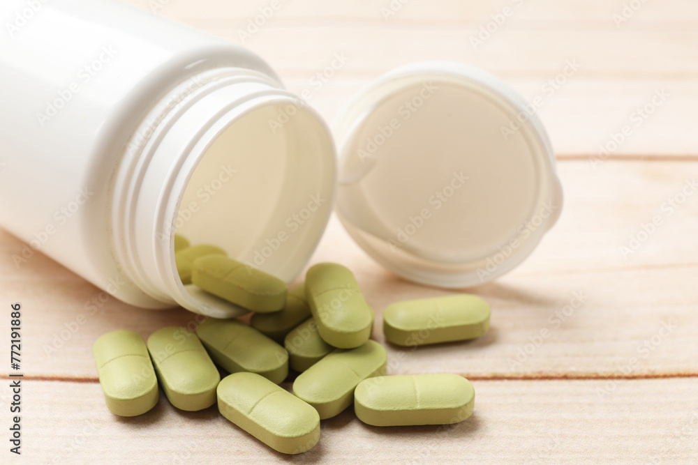 Bottle and vitamin pills on wooden table, closeup Bottle and vitamin pills on wooden table, closeup