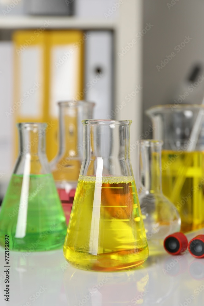 Laboratory analysis. Different glassware with liquids on white table indoors Laboratory analysis. Different glassware with liquids on white table indoors