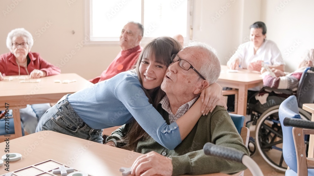 Obraz premium Happy young woman embracing grandfather in nursing home
