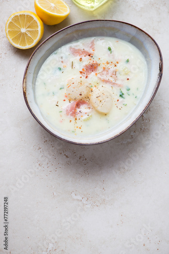 Bowl of scallop chowder on a light-beige stone background, high angle view, vertical shot, copy space