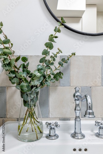 White vase with terrestrial plant on table beside mirror in interior design