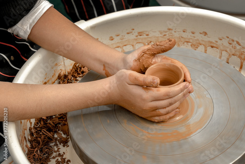 Children's hands create pottery on a potter's wheel during a master class on an outdoor playground