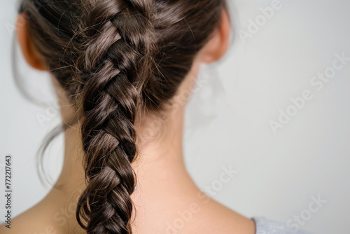 Close-up image of a woman featuring a detailed fishtail braid against a neutral background