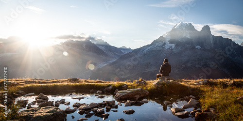 Panoramic view of a seated person watching the sunrise in mountains