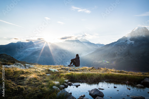Seated person watching the sunrise in mountains