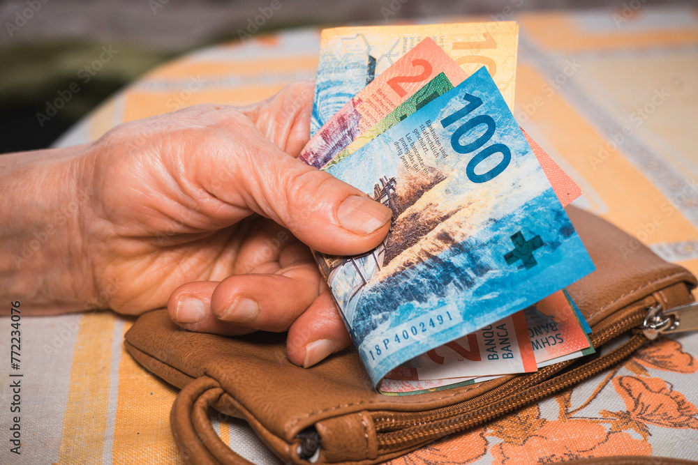 a small amount of Swiss francs in the hands of a pensioner, Financial concept, Problems of older people in Switzerland