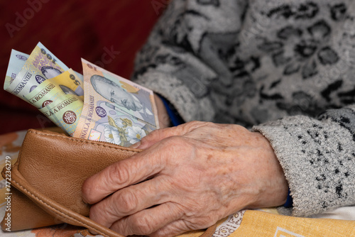 An old woman takes out a small amount of Romanian lei from her wallet, Financial concept, Rising cost of living and difficulties of retirees in Romania