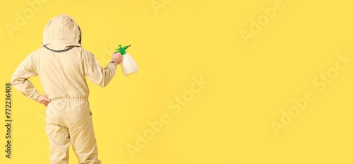 Male beekeeper with sprayer on yellow background, back view. Banner for design photo