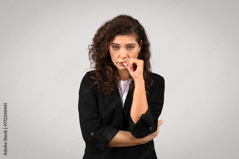 Curly-haired woman pondering with hand on chin Curly-haired woman pondering with hand on chin