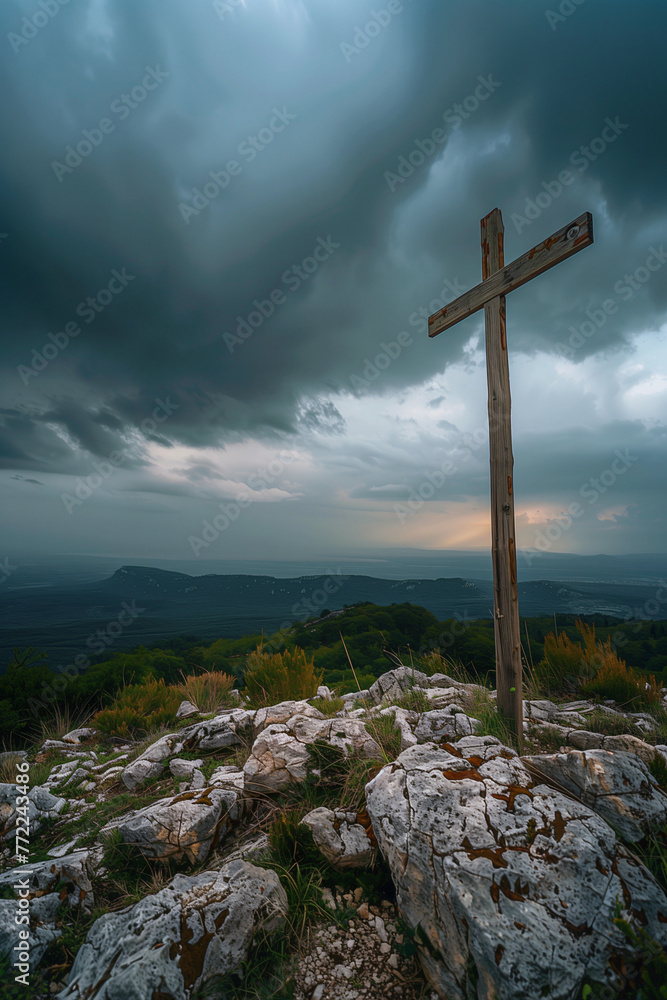 A wooden cross atop the mountain, with dark clouds in the background and a clear sky 