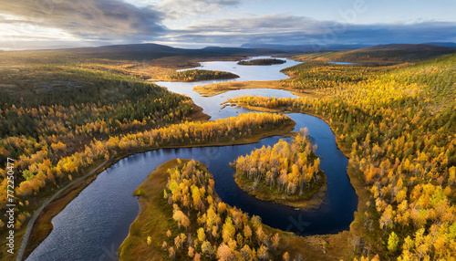 Drone capture of the Vistasjakka River, showcasing its meandering path, adjacent lakes, birch trees lining the banks, and colorful autumn scenery near Nikkaluokta in Norrbotten County, northern Sweden photo