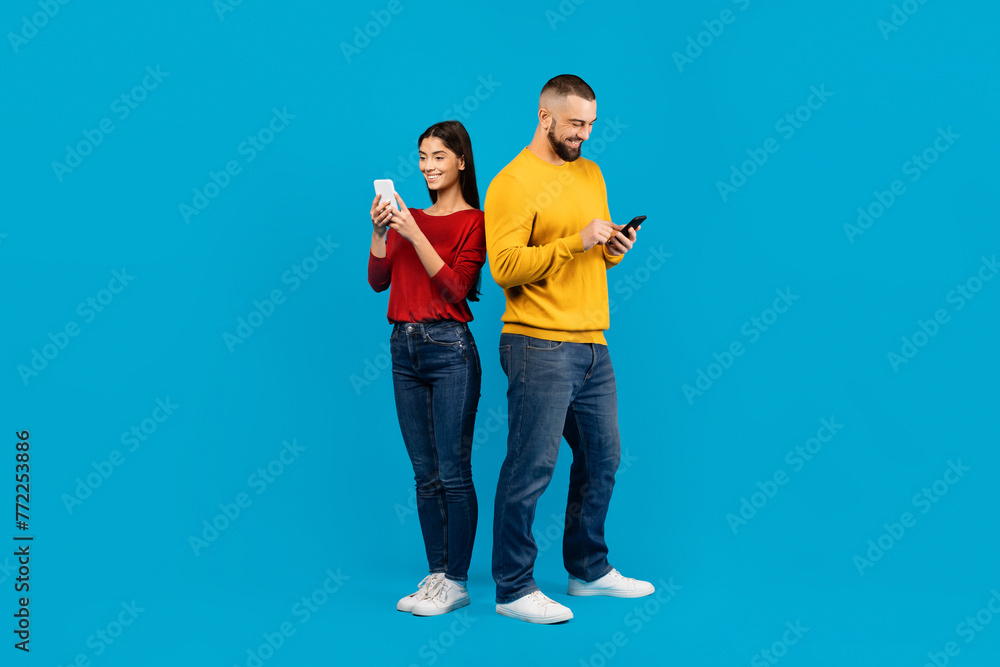 Fototapeta premium Young Man and Woman Using Smartphones Against Blue Background