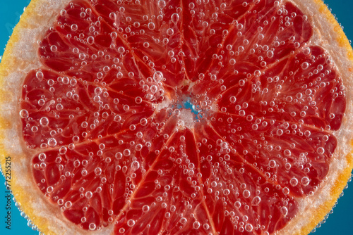 Close up view of a slice of grapefruit in soda water with bubbles. Summer drink concept.