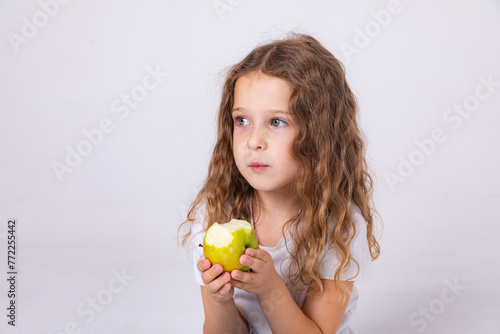 Cute child smiling bites apple. nutrition for caries prevention. portrait of little girl with fruit on white background. kid eating healthy food, snack. teeth, dental health, smile. children dentistry