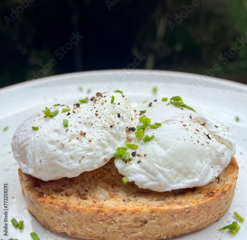 close up of two soft poached eggs with chives