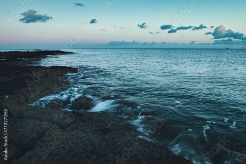 Stunning shot of a blue ocean, with waves rolling along the shoreline