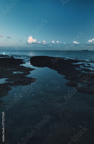 Tranquil blue seascape featuring large rocks  jutting up from the tranquil ocean waters below photo