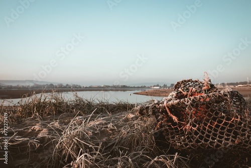 Pile of old frozen fishing nets on a grassy area next to a body of water in Bembridge harbor