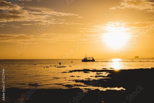 Fishing boat silhouette against sunrise sky in Isle of Wight UK © Wirestock