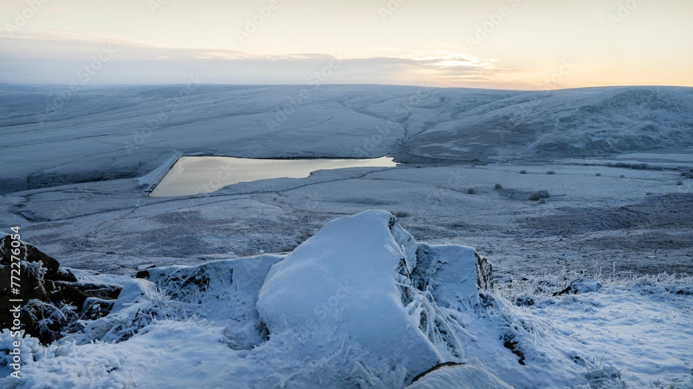 Scenic winter scene of a lake surrounded by snowy hills. Greater Manchester, England.