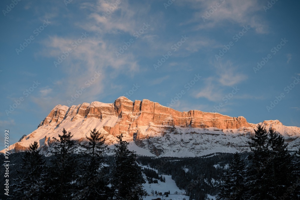 Scenic landscape featuring a range of snow-capped mountain peaks illuminated by golden morning light