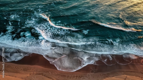 Aerial view of a beach with a brown sand and blue sea water with waves.
