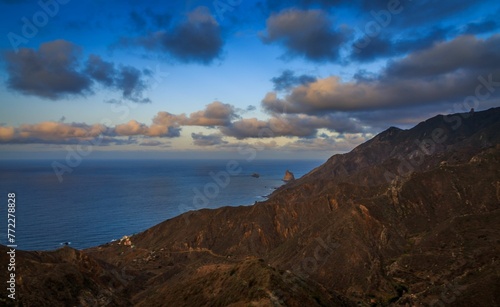 Tranquil ocean view overlooking a hillside with picturesque clouds at sunset