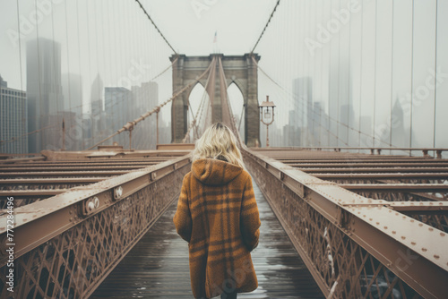 A young woman tourist in a Santa Claus hat walks during a snowfall in New York on Christmas Eve. Bridge and skyscrapers of NY on snowy day. Winter holidays in NYC. Snow is rare in New York. photo