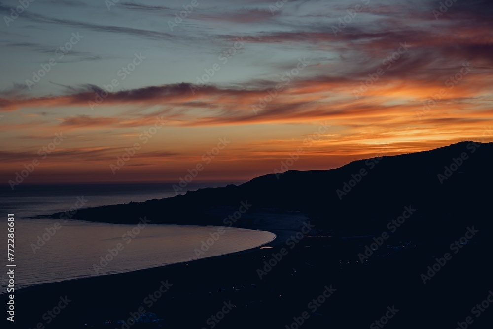 Fototapeta premium Beautiful scene of a vibrant sunset over the sandy beach and hills in Tarifa, Spain