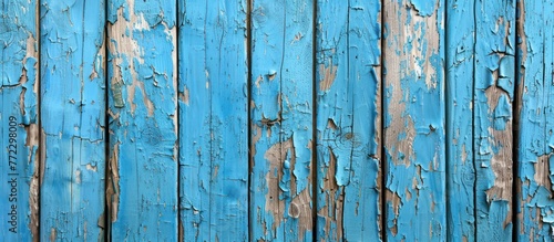 A close-up view of a weathered blue wooden wall with peeling paint, showcasing the effects of time and weather on the surface.