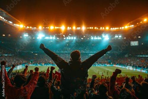 Enthusiastic fan raising arms in victory against a backdrop of a lit stadium © eggeeggjiew