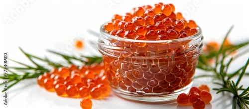Glass jar containing tasty red caviar against a white background.