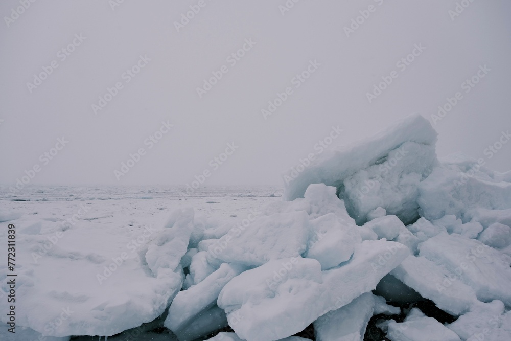 Serene winter landscape with large frozen ice blocks resting on a snowy shoreline
