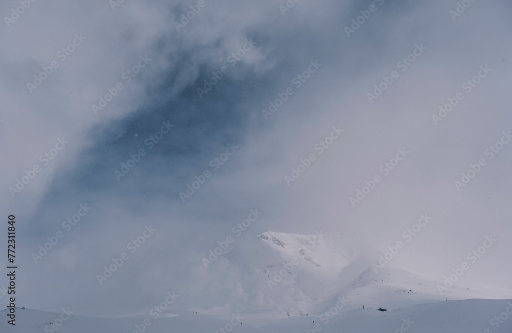 Idyllic winter scene of a snowy mountain with an empty ski slope in the center covered by fog Idyllic winter scene of a snowy mountain with an empty ski slope in the center covered by fog