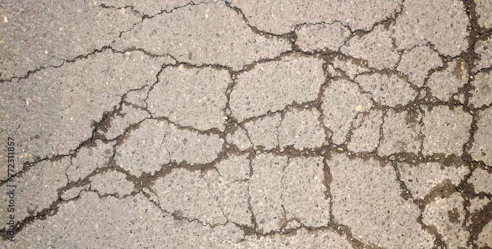 Obraz premium Road texture. Cracked concrete road covered with surface as background. Wall fragment with scratches and cracks. 