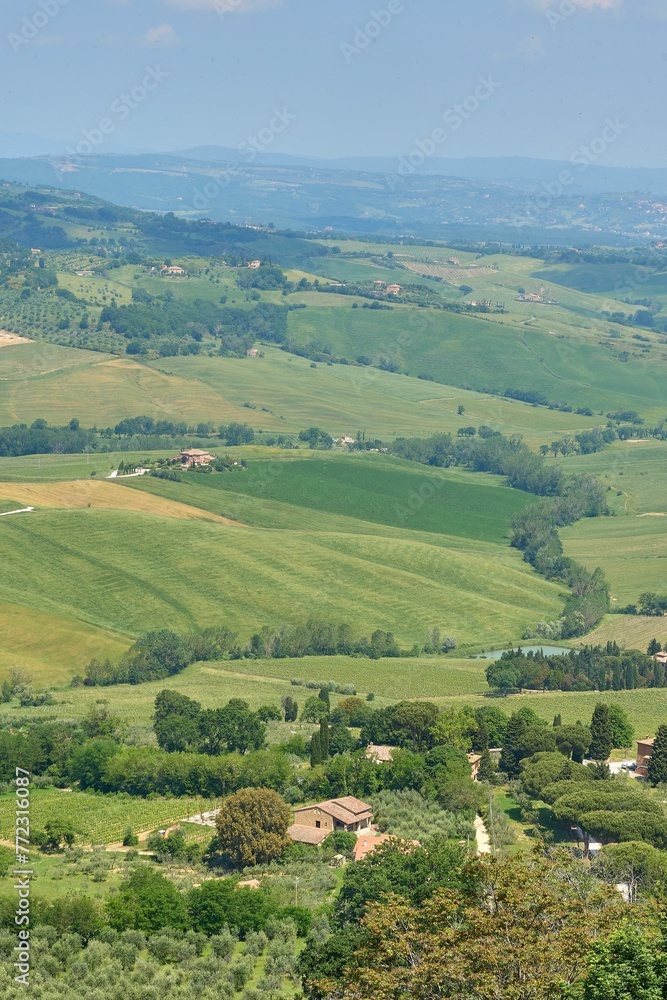 a large grassy hill with farm buildings and trees on the other side a large grassy hill with farm buildings and trees on the other side