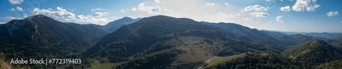 Scenic landscape of a green mountainous terrain featuring lush green trees, against the bright sky