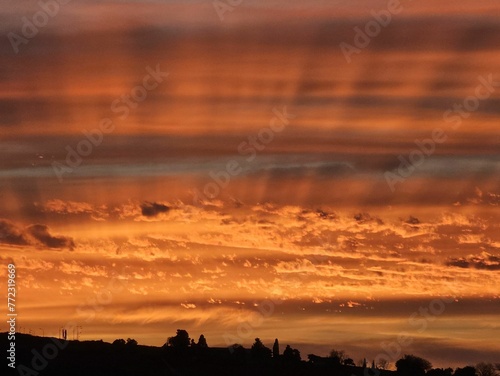 Beautiful red sunset illuminating the sky with fluffy clouds over a grassy plain
