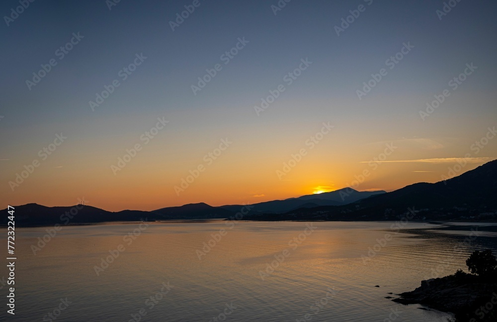 Scenic view of a sunset over the body of water surrounded by mountains.