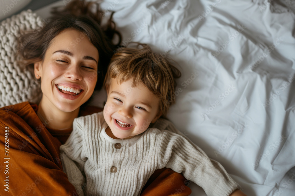 Candid Joyful mother and son sharing a laugh while lying in bed, capturing a moment of happiness and family love Candid Joyful mother and son sharing a laugh while lying in bed, capturing a moment of happiness and family love