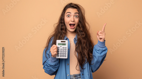 Mulher com expressão de surpresa segurando uma calculadora isolada no fundo bege