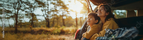 Asian Young mother and child enjoying a sunny car ride in nature, boy gazing out with joy and curiosity photo