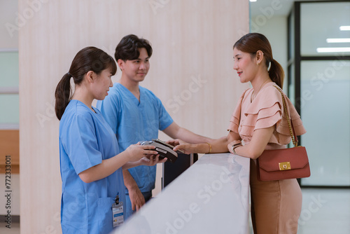 Woman is paying on reception desk in beauty treatment clinic using mobile phone
