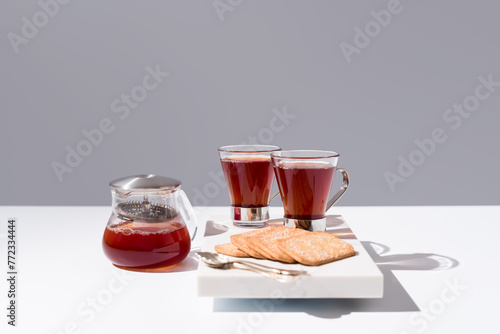 Té rojo con pasteles y dulces sobre mármol y fondo gris	