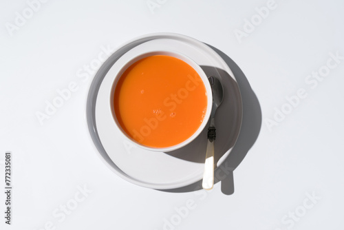 Sopa de zanahoria en un plato sobre fondo gris y blanco. Vista superior