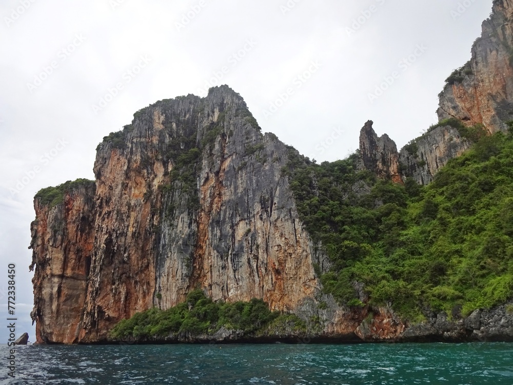 The serene blue sea is complemented by a majestic mountain towering above it, PHI PHI ISLAND, THAILAND 